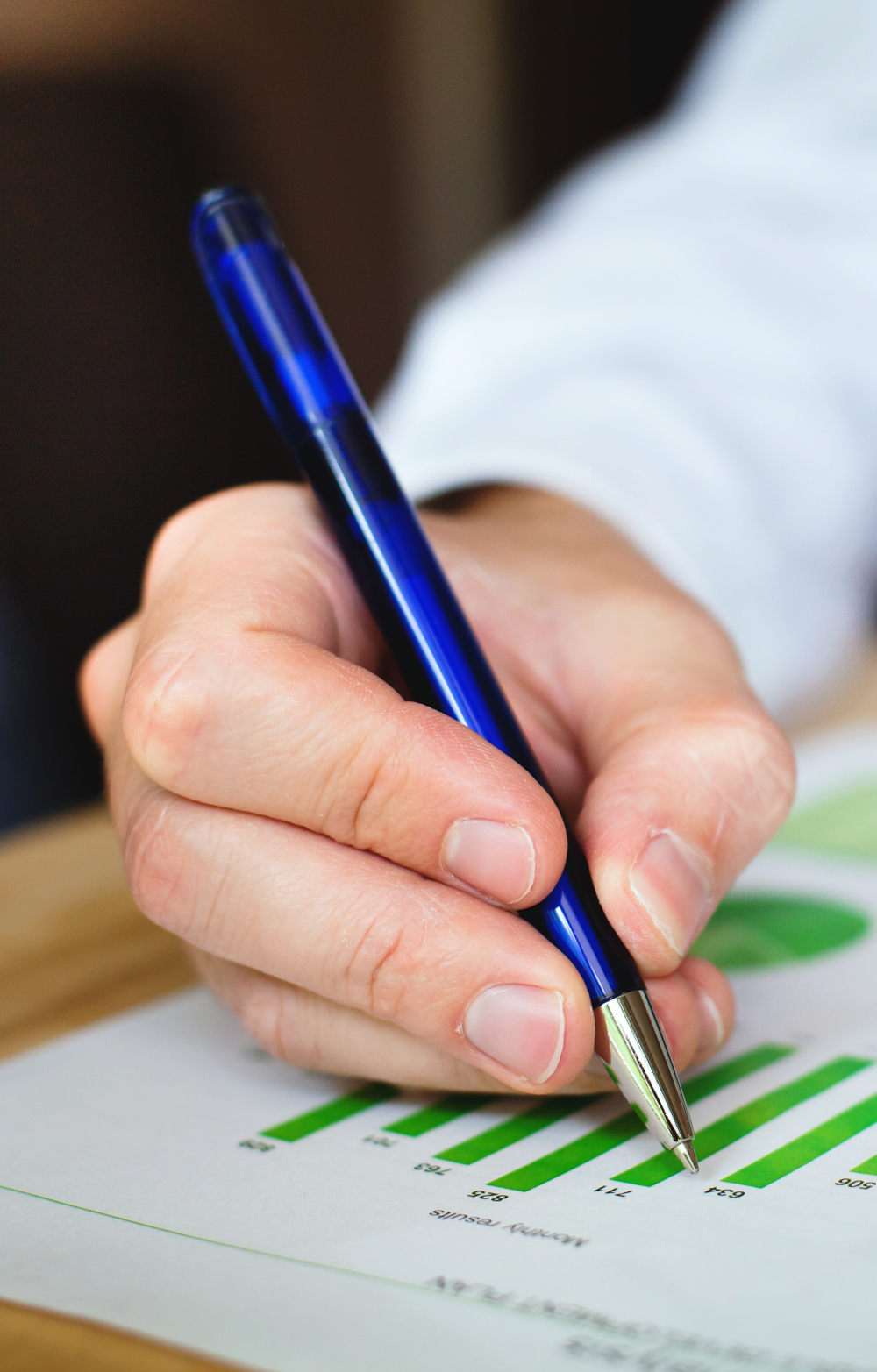 hand holding a pen to analyse a statistical chart