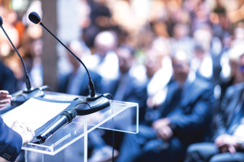 conference room full of people and a speaker at a lectern